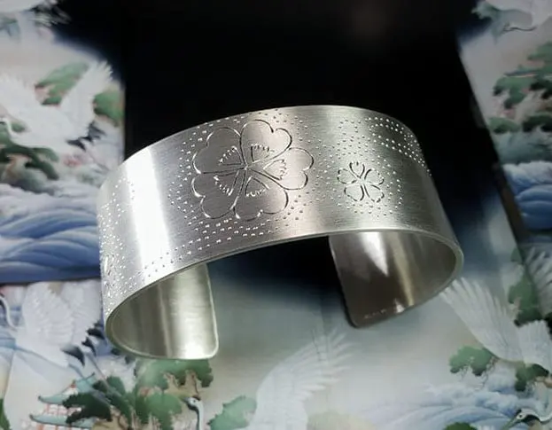 Zilveren klemarmband met handgravure van klavertjes bij de beek. Silver cuff with handengraved clovers. Oogst goudsmeden Amsterdam.