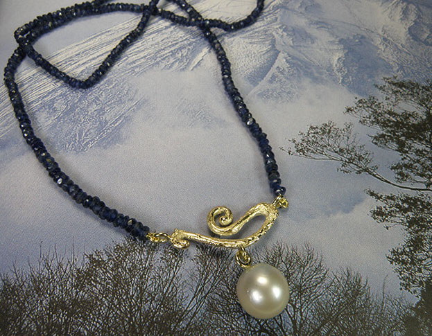 Blog about sapphire. Sapphire necklace with yellow gold Curl and a pearl. Design by Oogst studio in Amsterdam.