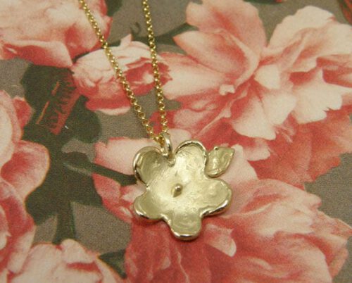 Geelgouden bloemetjeshanger aan fijn ankercollier. Yellow golden flower pendant on fine necklace. Uit het Oogst atelier Amsterdam.