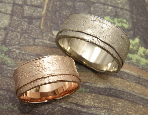 Trouwringen 'Erosie'. Roodgouden brede structuur ring met smalle laag. Witgouden brede structuur ring met brede laag. Wedding rings 'Erosion'. Rose golden structure ring with small layer. White golden structure ring with small layer. Oogst goudsmeden Amsterdam.