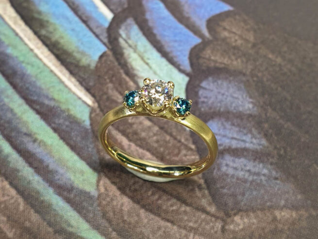 Verlovingsring Eenvoud geelgoud met diamant en blauwe diamant. Engagement ring Simplicity with diamond and 2 blue diamonds. Oogst goudsmid Amsterdam.