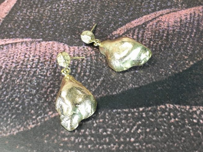 Geelgouden oorsieraden 'Wolken' met een hoekig kristal en steker. Ontwerp van Oogst goudsmid Amsterdam uit de Amorf vs Kristallijn collectie.