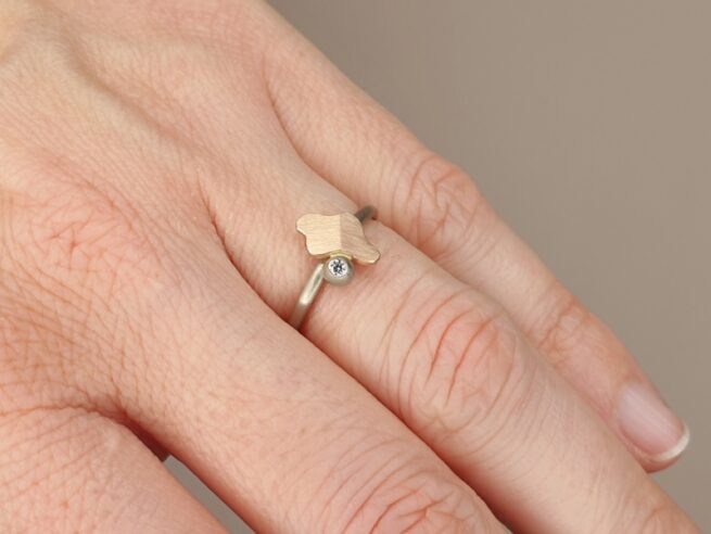 Witgouden ring 'Vouwen' met roodgouden element en bes met 0,03 ct diamant. Ontwerp van Oogst goudsmid in Amsterdam uit de Amorf vs Kristallijn collectie.