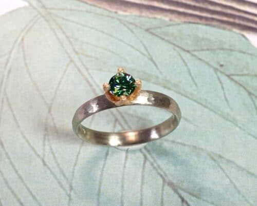 Witgouden 'Ritme'ring met hamerslag en groene diamant in een roodgouden tulpchaton.