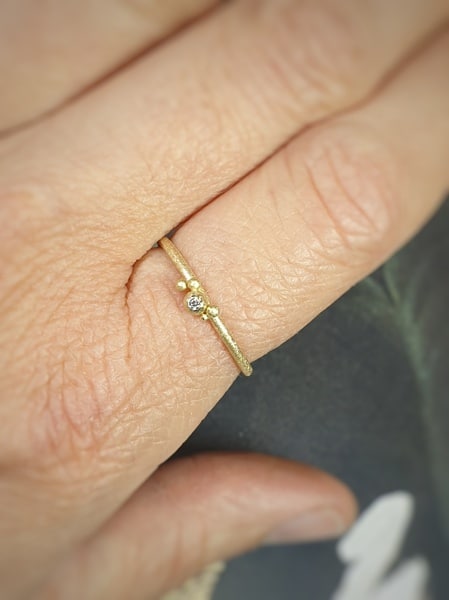 Delicate yellow gold ‘Berries’ ring with cute berries and a 0,015 ct brilliant cut diamond. Shown on the hand.Oogst jewellery design
