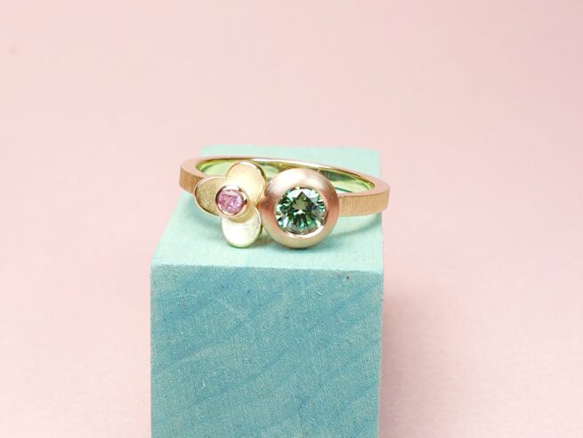 Yellow gold Boletus ring with a 0,35 ct paraiba green diamond and a 0,06 ct pink sapphire in a flower. Playful one-of-a-kind design by Oogst Jewellery.