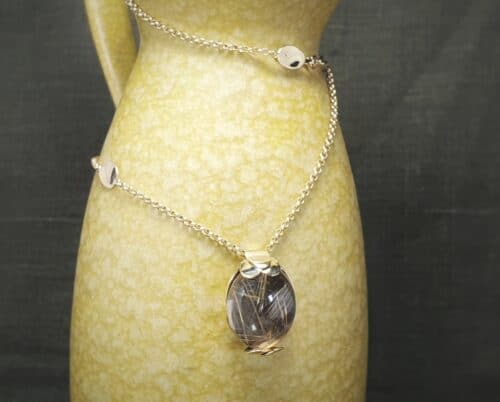 Golden necklace with a rutile quartz pendant with leaves. Design by Oogst jewellery in Amsterdam