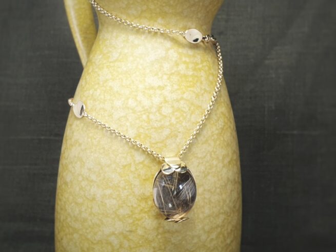 Golden necklace with a rutilated quartz pendant with leaves. Design by Oogst jewellery in Amsterdam