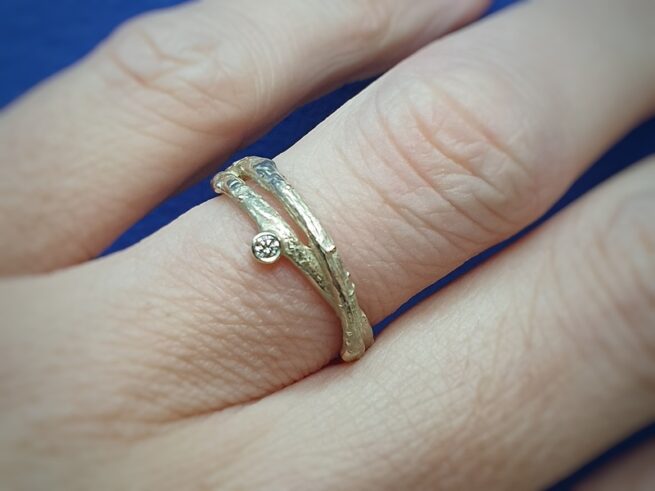 Geelgouden ring uit de Boomgaard serie, overkruist takje met diamant. Ontwerp van Oogst Sieraden in Amsterdam