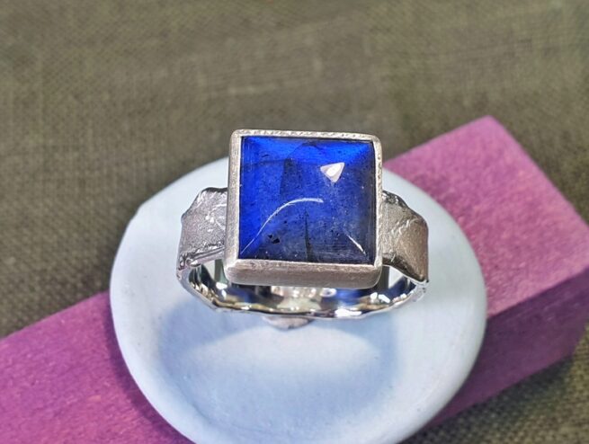 Silver ring from the ‘Erosion’ series with a shimmering square cut labradorite. Design by Oogst goldsmith in Amsterdam