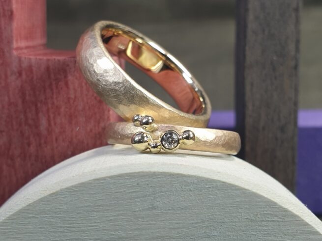 Yellow golden hammered 'Rhythm' wedding rings with small berries and diamond for her ring. Oogst goldsmith Amsterdam.