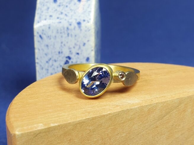 Ring met eigen ovaal geslepen saffier. Een twinkelende diamant ernaast en vrolijke blaadjes. Maatwerk uit het Oogst atelier Amsterdam.