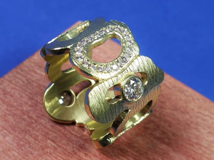 Geelgouden ring Amorf met roze diamant rondom. Open vormen met spitse hamerslag en sprankelende diamanten. Eenmalig ontwerp van Oogst Sieraden.