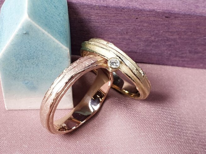 Rose gold and yellow gold Erosion textured wedding ring, with a diamond for her. Oogst goldsmith Amsterdam