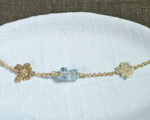 Yellow gold bracelet In Bloom with flower elements, hand engraving and aquamarine crystals. Design by Oogst in Amsterdam