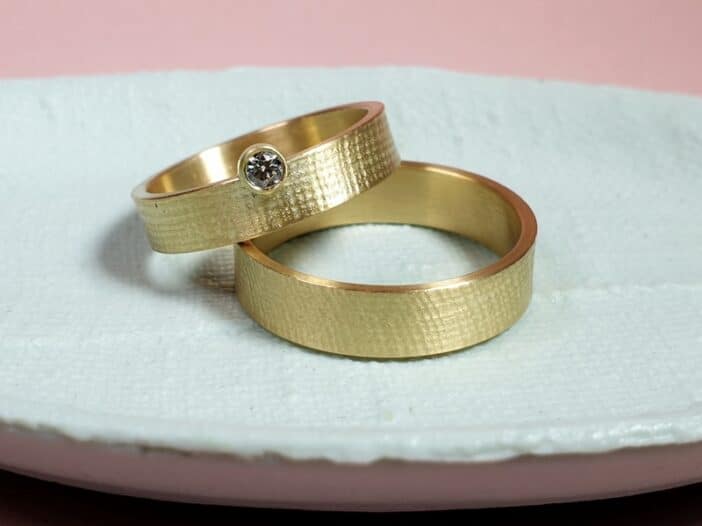 Trouwringen 'Linnen'. Geelgouden ring met 0,10 crt diamant en fijne structuur. Strak ontwerp van Oogst in Amsterdam.