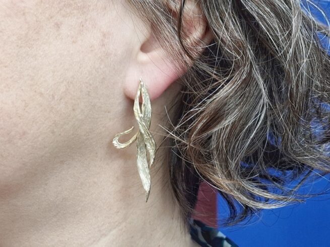 Yellow gold long ear studs 'Leaves'. Festive design by Oogst Jewellery in Amsterdam. Seen on the earlobe