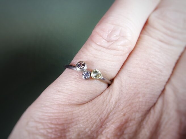 Verlovingsring Verzameling witgouden fijne ring met roosgeslepen diamant, besje en roze diamant in een boleet zetting. Verfijnde verlovingsring. Ontwerp van Oogst Goudsmeden in Amsterdam. Om de vinger geschoven.