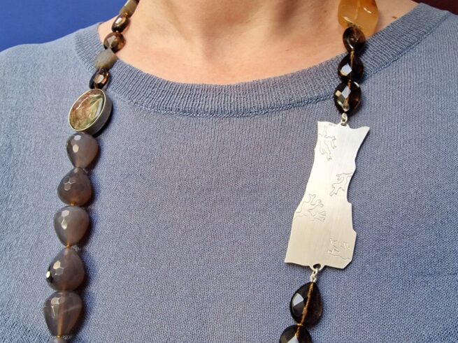 Edelsteen collier met zilveren rotsornament, rutielkwarts, agaat, rookkwarts, saffier, gedragen om hals. Statement ketting van Oogst Goudsmid in Amsterdam