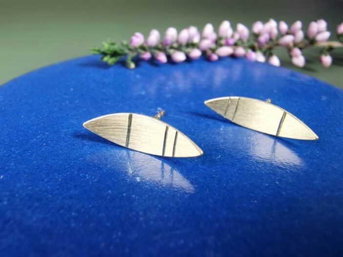 Geelgouden oorstekers, linsvorm met streepjes Mackintosh ornament. Sieraad ontwerp van Oogst Goudsmeden in Amsterdam.