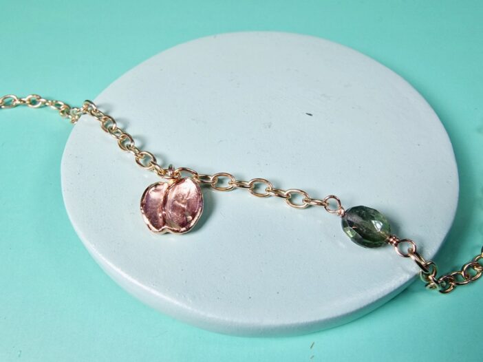 Roodgouden bedel armband met Mackintosh ornament en groene toermalijn. Verfijnd ontwerp van Oogst in Amsterdam