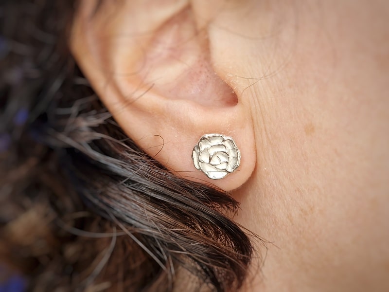 Zilveren oorstekers Mackintosh roosjes. Verfijnde roos oorbellen in het oor. Ontwerp uit het Oogst atelier.
