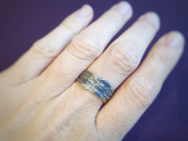 Zilveren ring met rots structuur, om de vinger gedragen. Uit de Kust serie. Oogst Sieraden in Amsterdam