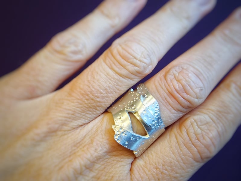 Zilveren ring overlappend zeewier. Sieraad ontwerp van Oogst in Amsterdam. Om de vinger