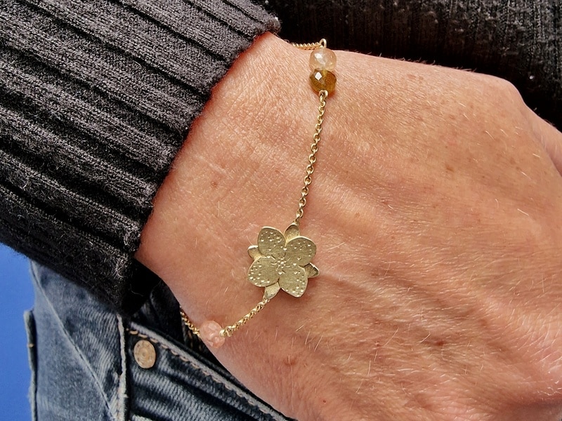 Yellow gold 'In bloom' bracelet with a playful flower and several warm colours tourmaline as accent. See on the wrist. Oogst Jewellery design in Amsterdam
