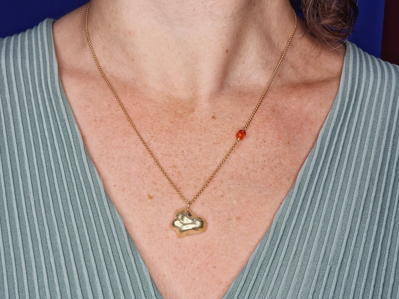 Golden necklace Cloud with an accent of Carnelian.  Seen on model. Whimsical jewellery design by Oogst in Amsterdam.