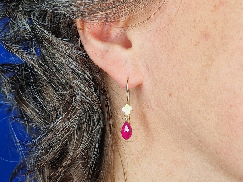 Yellow gold 'In bloom' earrings with a briolet cut ruby and cute flower. Refined pair by Oogst in Amsterdam. Seen on the earlobe.