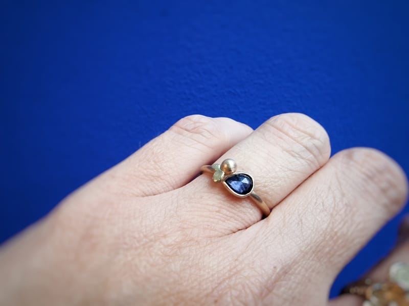 Rosé gold ring with pearshaped sapphire, yelow gold leaves and a cute berry. From the 'Berries' series in the handmade Oogst collection.   On the finger.