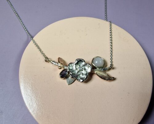 Birth jewel. White gold necklace with moonstone, diamond and alexandrite. With playful blossom and rose gold leaves. Created by Oogst.