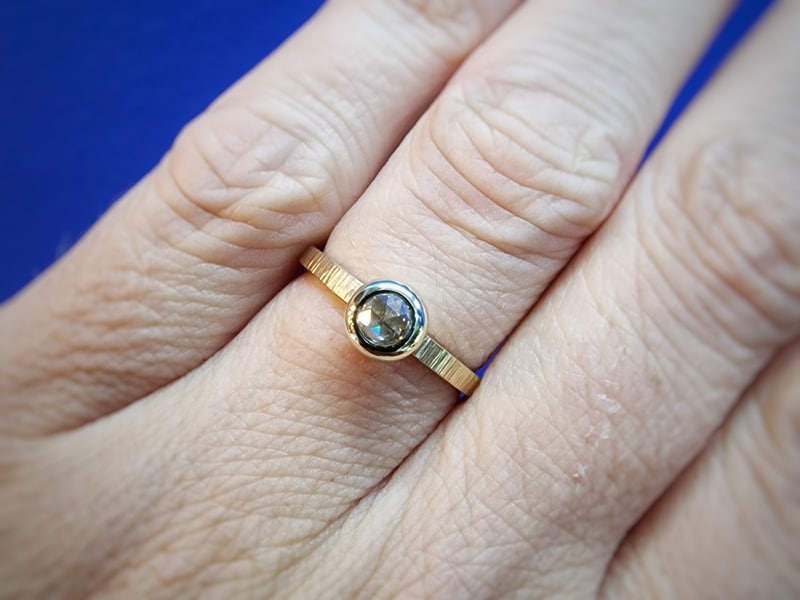 Elegant engagement ring from the 'Rhythm' series with a rose cut diamond in a Boletus setting. Created at the Oogst goldsmith studio. As seen on the finger.