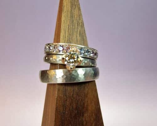 White gold wedding ring 'Rhythm' with hammering. Engagement ring with a 0,36 ct diamond light brown with fine hammering and playful dots. Stack ring white gold eternity ring pavé set all around spinel. Modern classics created in the Oogst studio.