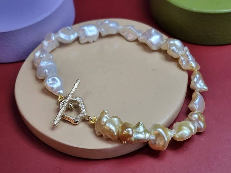 Amorf armband met Zuidzee Keshi verlopend van wit naar goudtinten. Natuurlijke kleurnuances. Uit het Oogst atelier. Met geelgouden sluiting met diamanten.