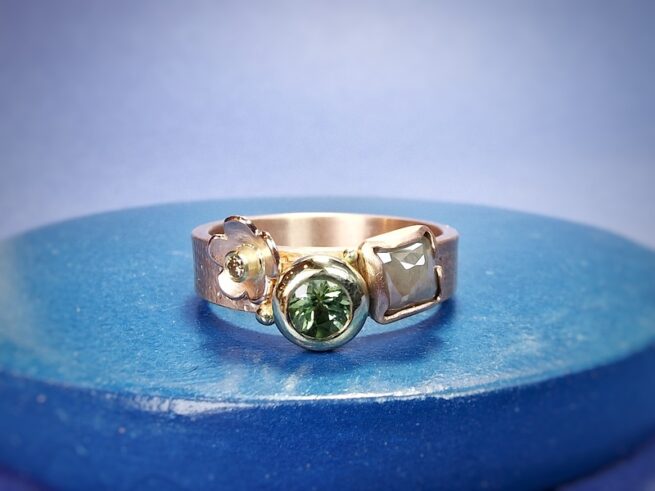 Roodgouden 'Verzameling' ring met speelse mix van linnen textuur en stipjes, naturel diamant, groene toermalijn en bloempje met een briljant geslepen diamant. Oogst Original.