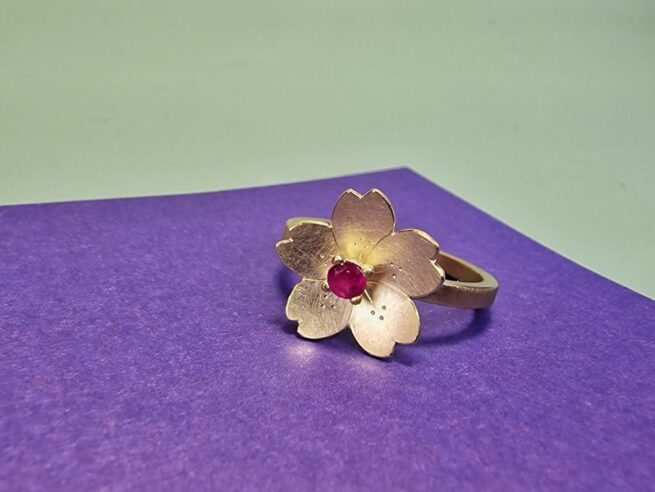 Edelsteen ring met geelgouden Sakura, de kersenbloesem, met verfijnde handgravure. Met Robijn, de geboortesteen van juli. Bijzonder stuk van Oogst.
