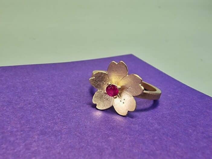 Edelsteen ring met geelgouden Sakura, de  kersenbloesem, met verfijnde handgravure. Met Robijn, de geboortesteen van juli. Bijzonder stuk van Oogst.
