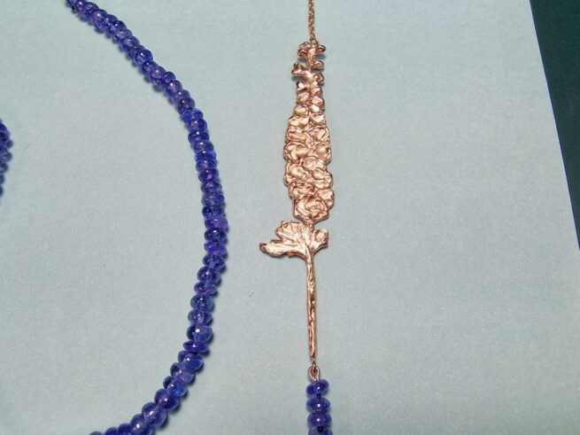 Collier Ridderspoor roodgoud met tanzaniet snoer. Maandbloem van juli. Moderne klassieker van Oogst. detail van de bloem.