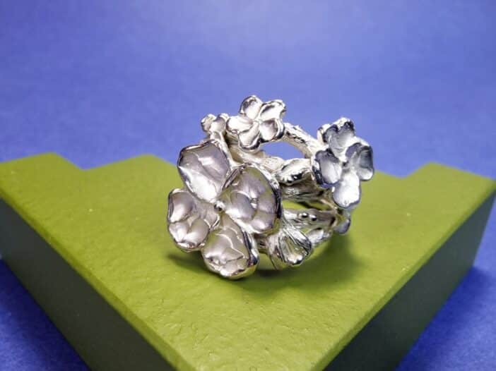 Standout silver twig ring with bold blossoms, a small leaf and a cute flower bud from the 'Japonais' series. Unique design by Oogst.