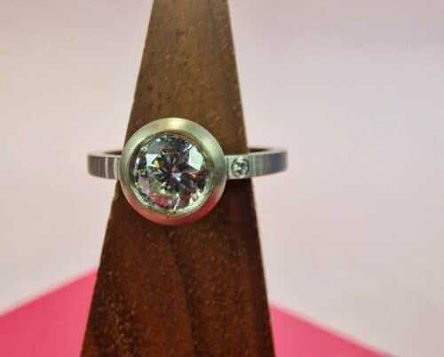 Ring 'Boletus'. White gold slim ring with pointy hammering and a brilliant cut heirloom diamond in a rounded setting and another own diamond set into the band. Custom created at the Oogst studio