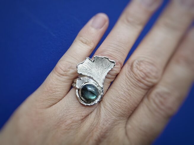 Uitgesproken Ginkgo ring in zilver met een prachtige labradoriet cabochon. Blikvanger van Oogst Goudsmeden. Om de vinger gezien.