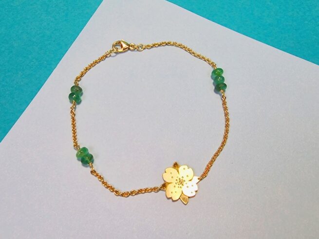 Geelgouden armband met smaragd en een bloem ertussen. Uit de 'In bloei' serie van Oogst Goudsmeden.