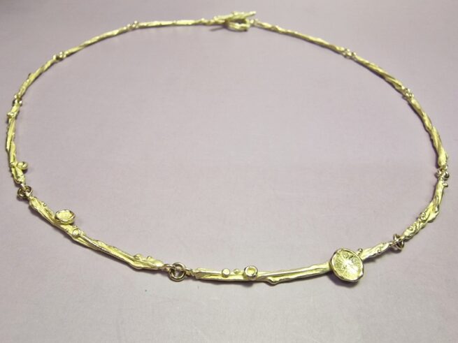 Geelgouden verfijnd collier uit de 'Twist' serie met subtiele details van zwammen, perziken en besjes. Oogst Goudsmeden