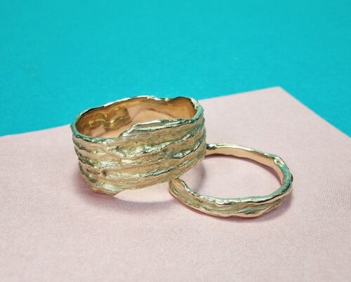 These yellow gold 'Twist' & 'Coast' wedding rings have curved lines and a nice mix of rugged texture and soft shimmer. Designed by Oogst Jewellery.