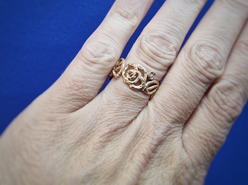 Mackintosh ring in roodgoud. Met open motieven van blaadjes en roos rondom. Uitgesproken en elegante statement ring uit het Oogst atelier. Om de vinger gezien.