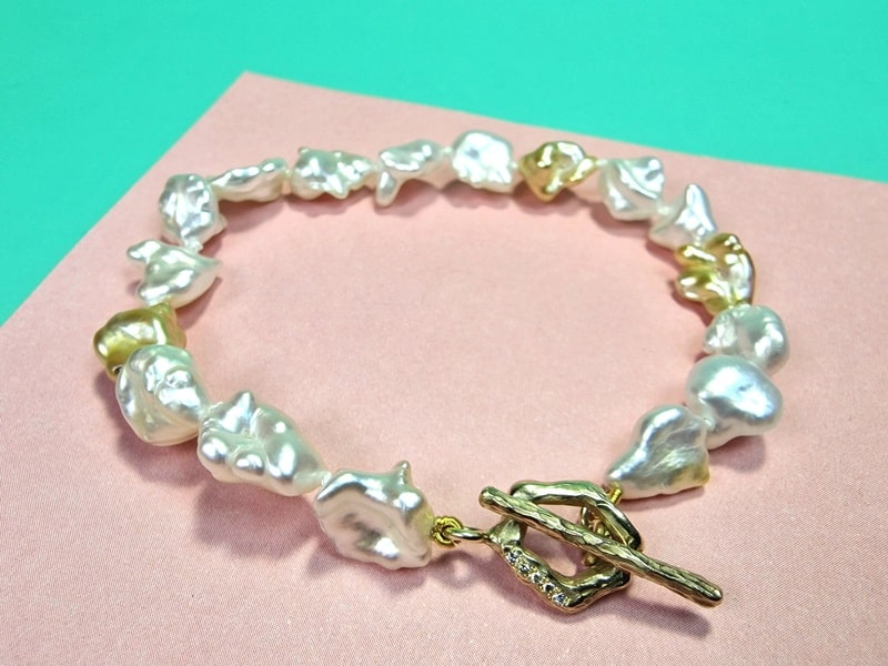 Pearl bracelet with yellow gold 'Amorphous' clasp with diamonds. South Sea keshi pearls in white and gold tones. Unique piece by Oogst Jewellery.