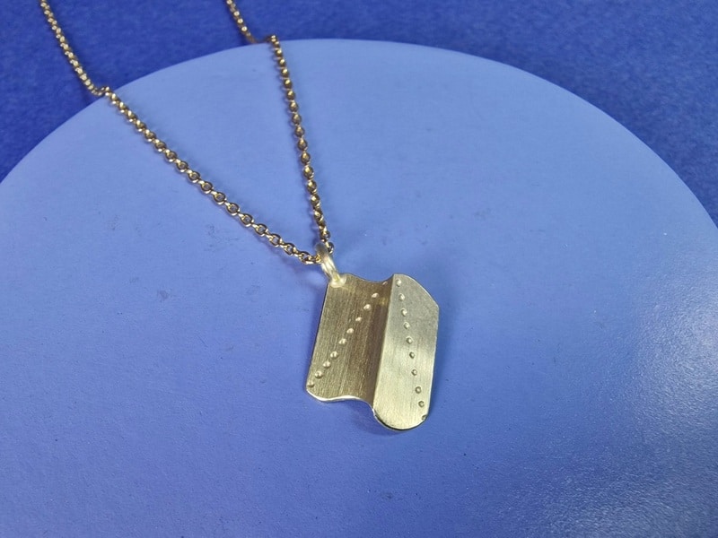 Geelgouden hanger uit Vouwen serie, amorfe vorm met vouw en stip patroon. Uit het Oogst atelier.