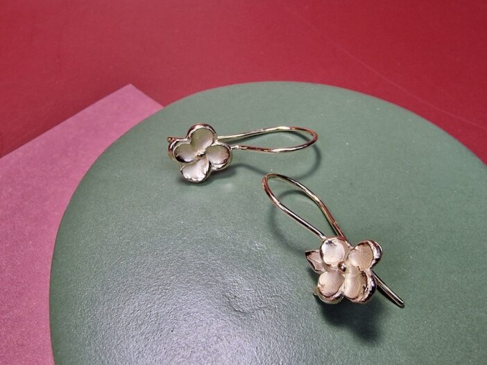 Tijdloze geelgouden oorsieraden met bloesems met een elegante krul. One-of-a-kind asymmetrisch paar, ontwerp uit het Oogst goudsmid atelier.